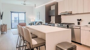 Una cucina moderna con isola centrale, zona pranzo con sedie e vista all'esterno.