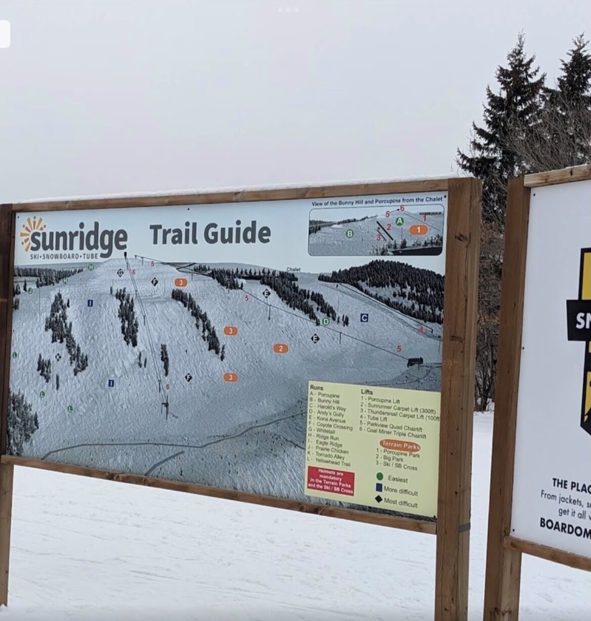 A trail guide sign at a ski resort with marked runs and lifts, indicating the layout of the ski trails and lift systems.
