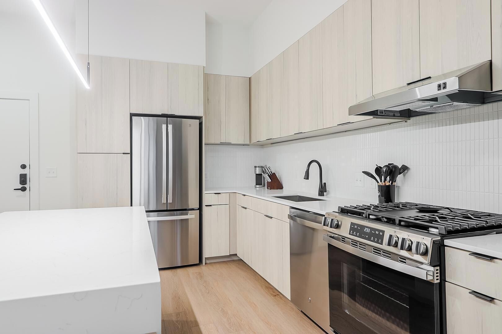 A modern kitchen with a stainless steel refrigerator, a gas stove, and a dishwasher.