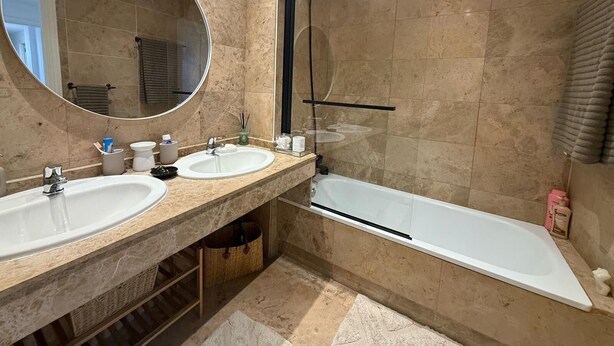 Une salle de bain moderne avec deux lavabos, un grand miroir, une douche et une baignoire.