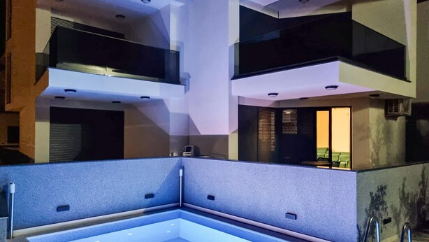 En moderne swimmingpool indendørs med geometrisk design, indbyggede siddepladser og udsigt til det fri.