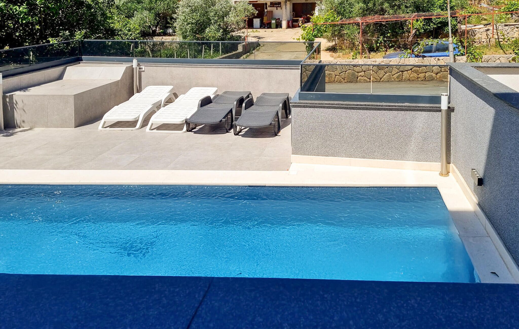 Une piscine sur le toit, dotée de chaises longues et bordée d’un mur en pierre.