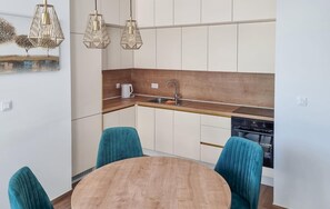 A modern kitchen with a wooden countertop, a sink, and a stove. There are two teal chairs around a wooden table. - Beautiful apartment in Vrboska with WiFi (Vrboska)