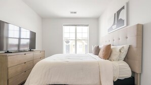 Una camera da letto con un letto, una televisione su una cassettiera e una finestra con persiane.