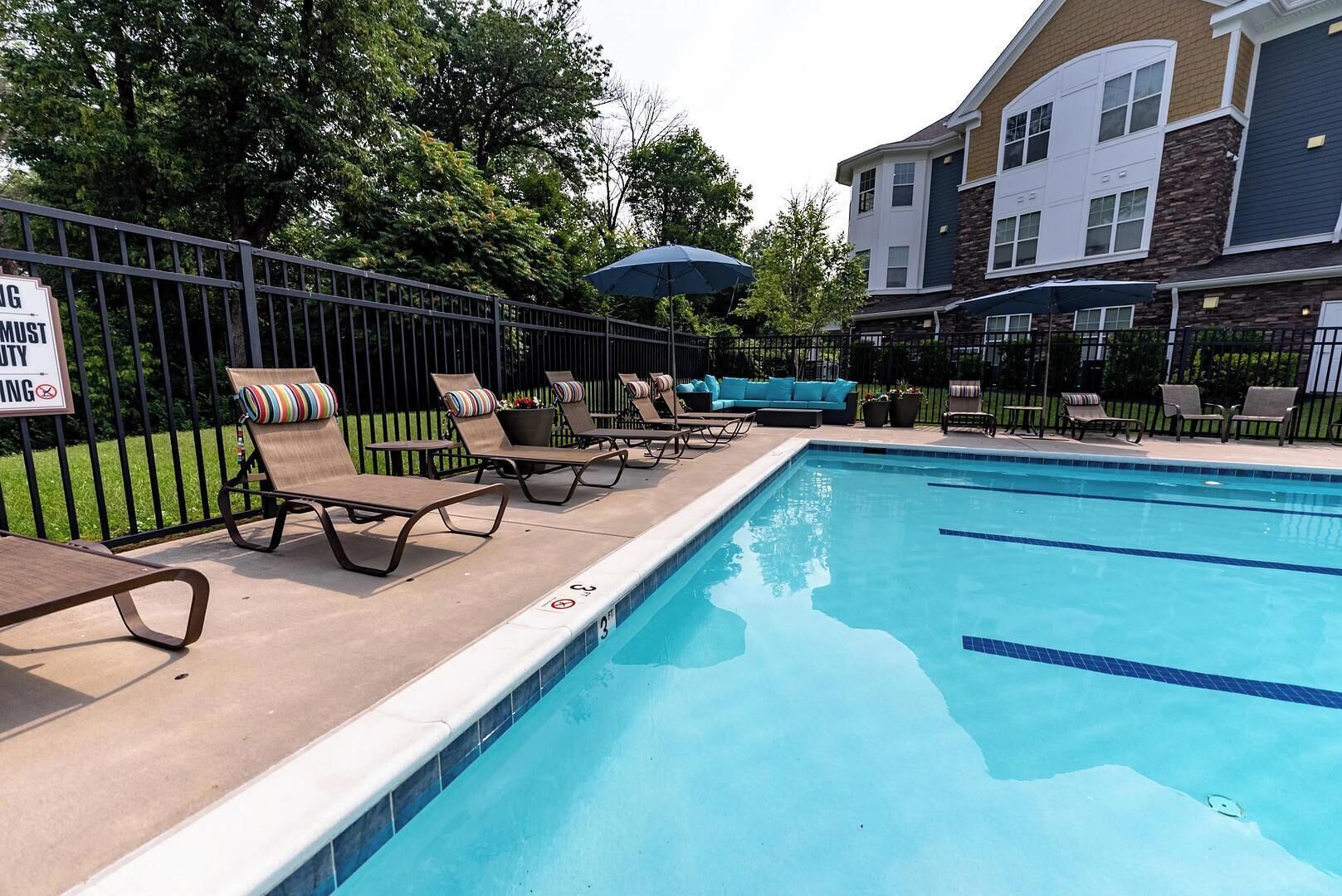 A swimming pool with lounge chairs and a fenced area.