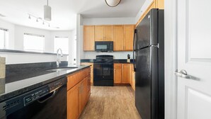 Una cucina moderna con mobili in legno, un frigorifero nero, un forno a microonde ed una lavastoviglie.