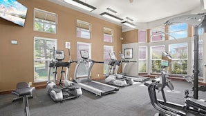 Ein Fitnessstudio mit Laufbändern, Crosstrainern und einem Ergometer.