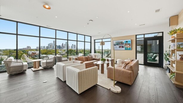 A spacious living area with large windows, a city view, and modern furniture. - Landing | Chic 2BD, Gym, Courtyard (Houston)