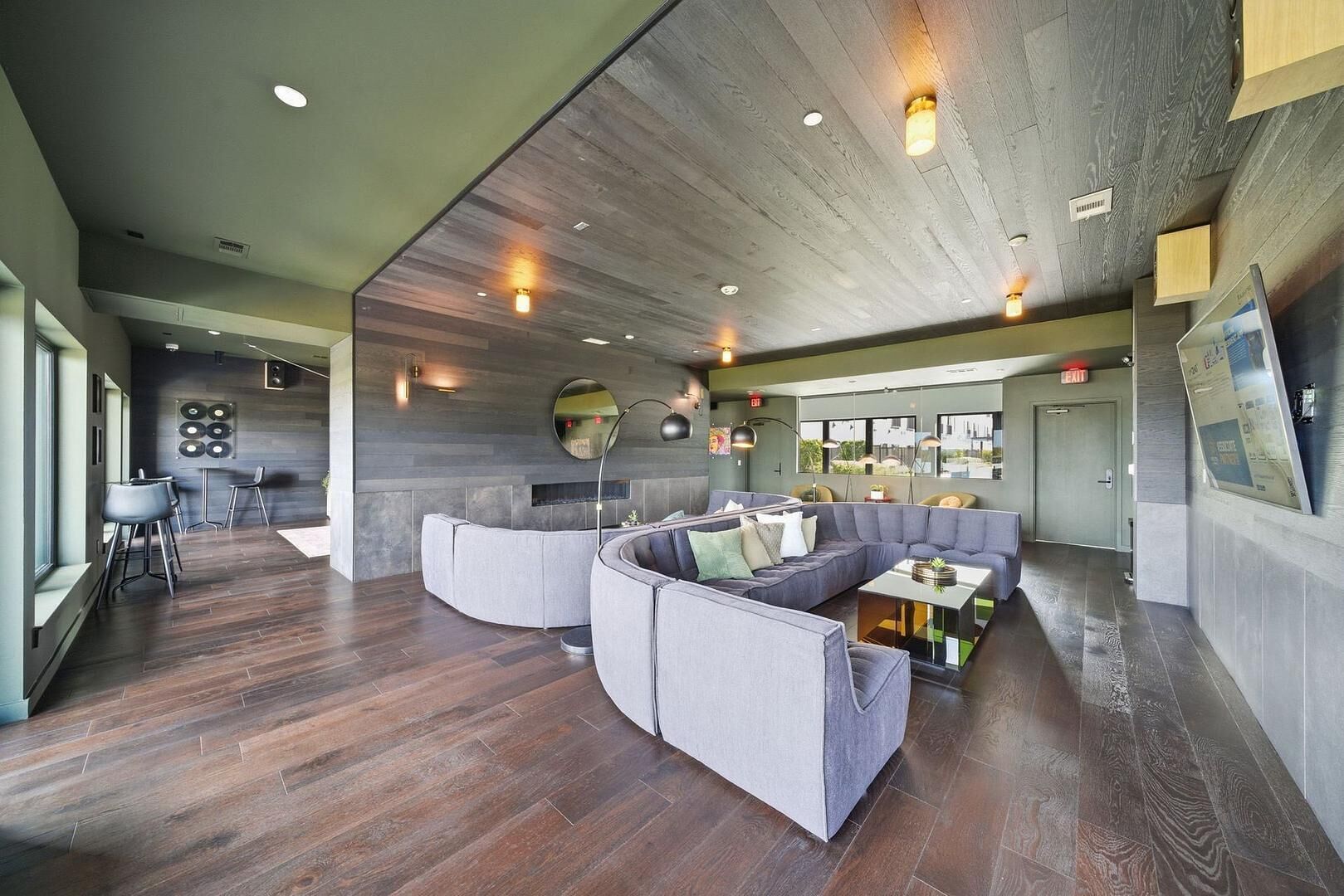 Un espace salon moderne avec un canapé incurvé, une petite table et un coin bar équipé de tabourets.