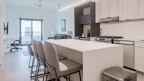 Una cocina moderna con una isla central, taburetes de bar, estufa y lavavajillas.