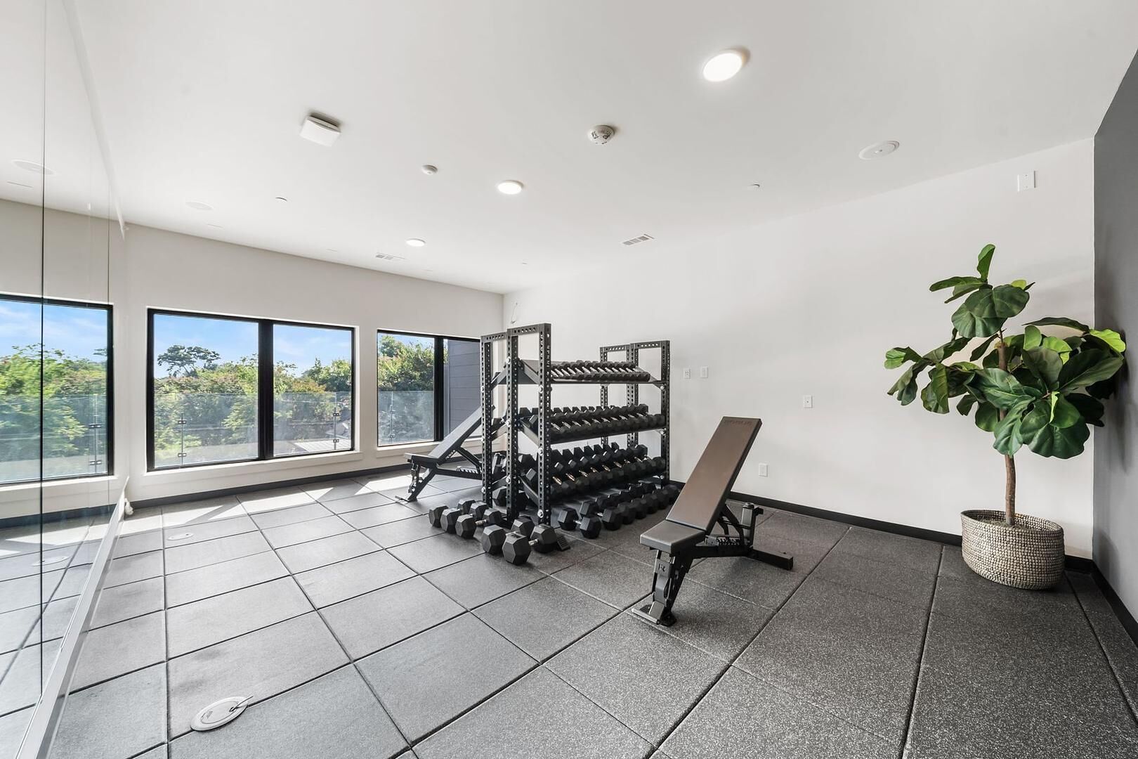 A gym with a weight rack, dumbbells, and a bench.