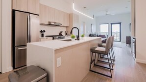 Une cuisine moderne dotée d’un îlot central, d’appareils électroménagers en acier inoxydable et d’un coin repas offrant une vue agréable.
