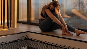 A person sitting on a bench by a large window with a view of a fence and hills. - Flowfort View Private Hottub & Sauna Cottagerześko (Stara Kamienica)