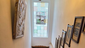 Eine Holztreppe mit Handlauf, ein Fenster mit Gittermuster und Bilder in Rahmen an der Wand.