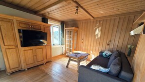 Ein Holzinterieur mit einer Couch, einem Tisch und Schränken.