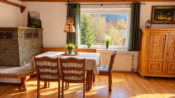 A dining area with a wooden table, chairs, and a window with a view of trees.