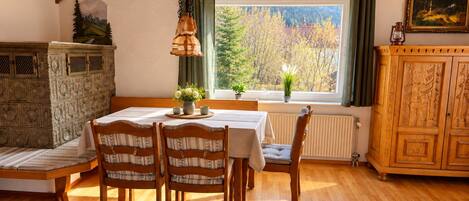 A dining area with a wooden table, chairs, and a window with a view of trees.