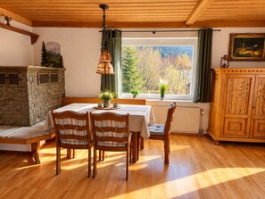 Ein Essbereich mit einem Holztisch, Stühlen und einem Fenster mit Blick auf Bäume.