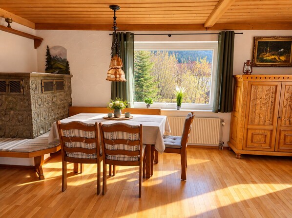 A dining area with a wooden table, chairs, and a window with a view of trees. - Albert Apartment: Quiet Vacation Rental on the Banks of the Altmühl *Air-Conditioned* (Pappenheim)