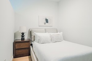 A bedroom with a bed, a nightstand, a lamp, and a wall-mounted artwork. - Landing | Spectacular Studio, Courtyard, Gym (Houston)
