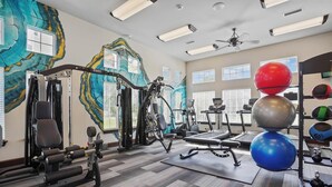 Ein Fitnessstudio mit verschiedenen Trainingsgeräten, darunter Kraftgeräte, Laufbänder und Gymbälle.
