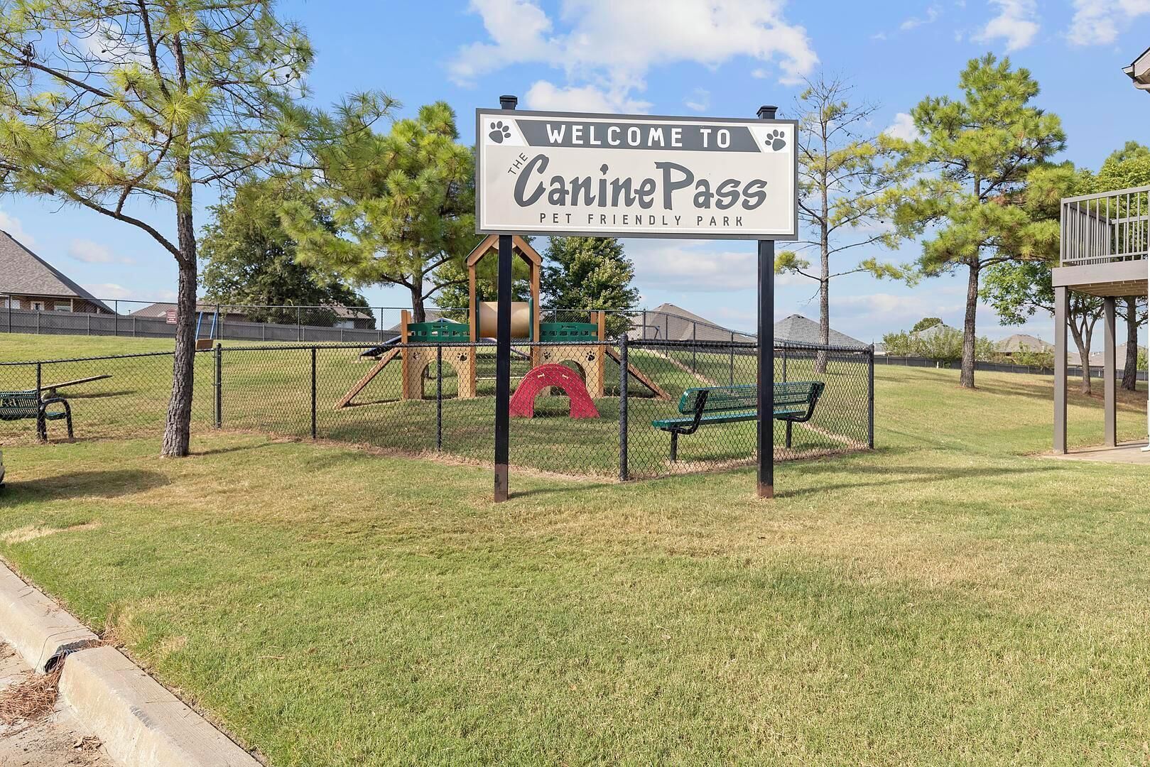 Un parc pour chiens clôturé, avec une pancarte indiquant : « Bienvenue au parc CaninePass, un espace accueillant les animaux de compagnie. »