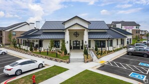 Un edificio moderno con un ingresso centrale, un parcheggio e un cartello che indica la disponibilità di appartamenti in affitto.