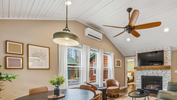 A cozy living room with a fireplace, ceiling fan, and dining area with chairs and a table. - Modern Woodsy Cabin, Walk to Sister Bay (Sister Bay)
