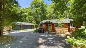 A cabin with a covered driveway, surrounded by dense forest. - Modern Woodsy Cabin, Walk to Sister Bay (Sister Bay)