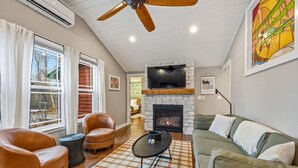 A living room with a fireplace, leather chairs, a sofa, and a ceiling fan. - Modern Woodsy Cabin, Walk to Sister Bay (Sister Bay)