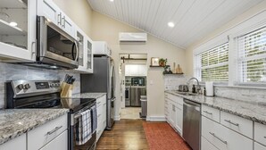 A modern kitchen with stainless steel appliances, white cabinetry, and a red rug. - Modern Woodsy Cabin, Walk to Sister Bay (Sister Bay)