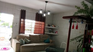 A living room with a sofa, a glass-top table, a bookshelf, and a hanging plant.