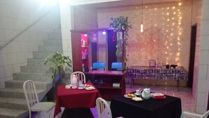 A dining area with a staircase, a table with a red tablecloth, and a table with a black tablecloth.