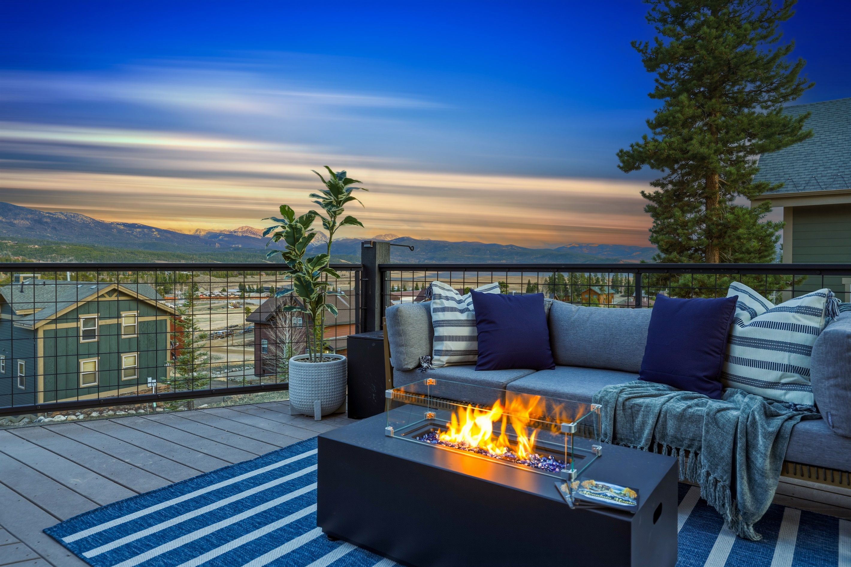 A deck with a fire feature, outdoor seating, and a view of mountains.