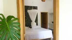 Una camera da letto con un letto, un muro in pietra, una porta di legno e una pianta grande.