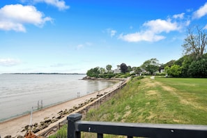 A coastal view with a beach, a grassy area, and a row of houses.