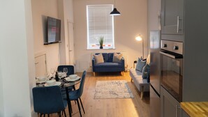 Un espace de vie compact comprenant un coin repas, un canapé et une kitchenette.