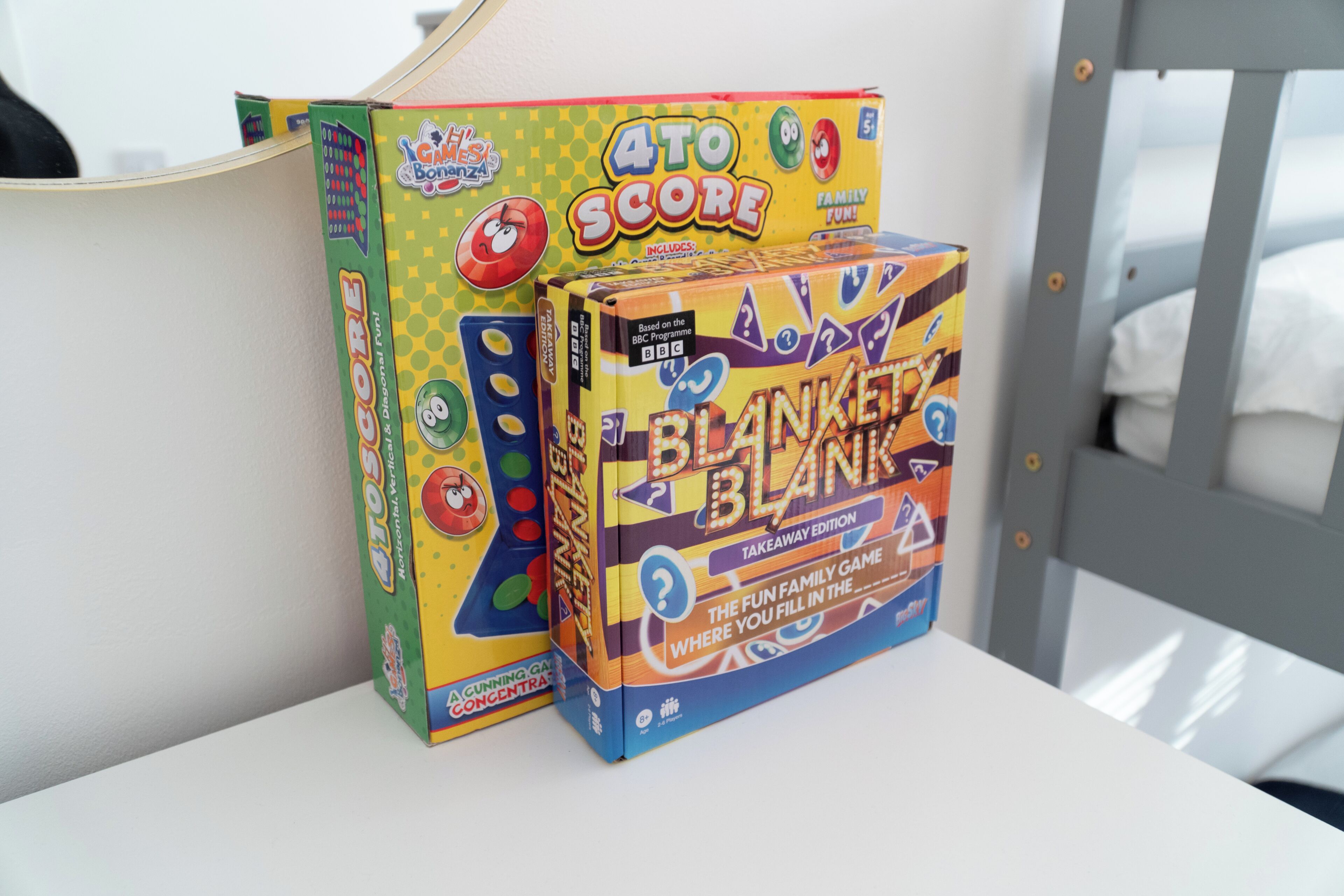 Twee spelletjes, '4 to Score' en 'Blanket Blank', op een wit oppervlak.