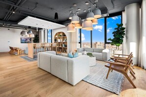 Ein modernes Wohnzimmer mit einer Eckcouch, Essbereich und großen Fenstern mit Blick auf die Stadt.