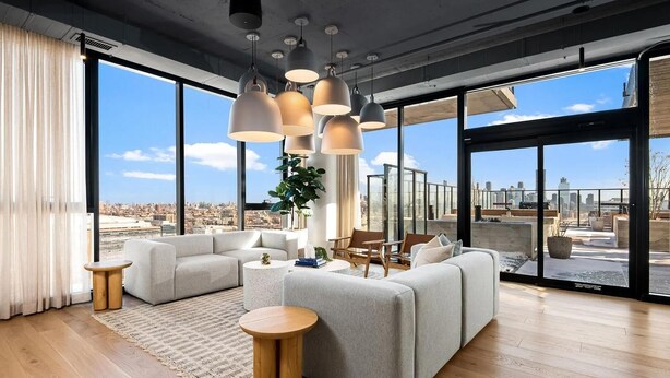 Uma sala de estar moderna com um sofá grande, mesa de centro redonda e luminárias pendentes.