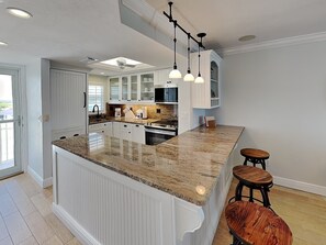 A kitchen with a central island, white cabinetry, and pendant lighting. - Pointe South 106 (Fort Myers Beach)