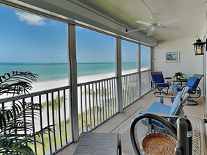 A balcony with a view of the beach, a ceiling fan, and blue chairs. - Pointe South 106 (Fort Myers Beach)