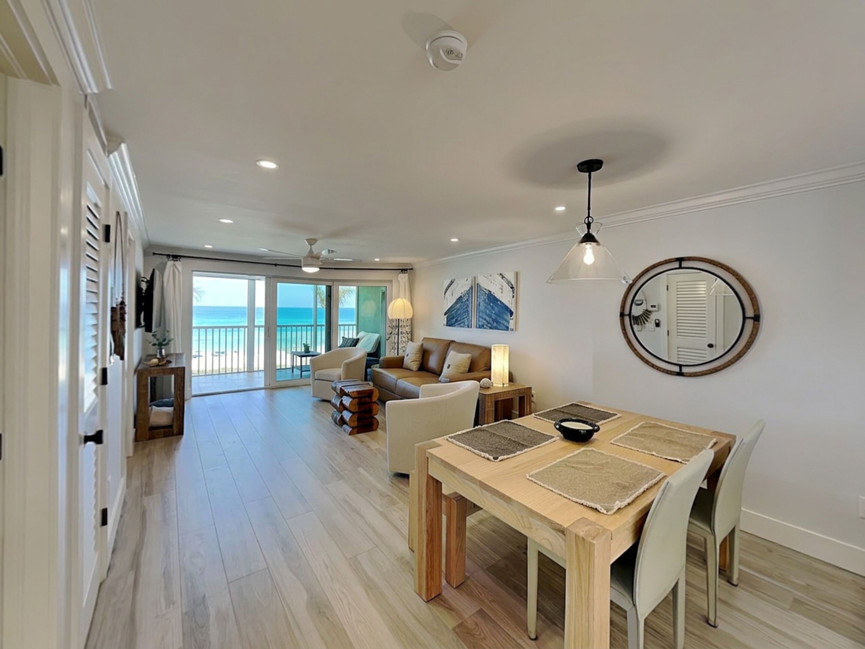 Een ruime woonkamer met balkon, een eettafel en uitzicht op de oceaan.