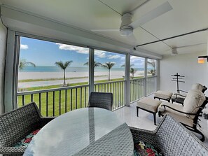 Ein Balkon mit Blick auf den Strand, ausgestattet mit Korbmöbeln und Deckenventilator.