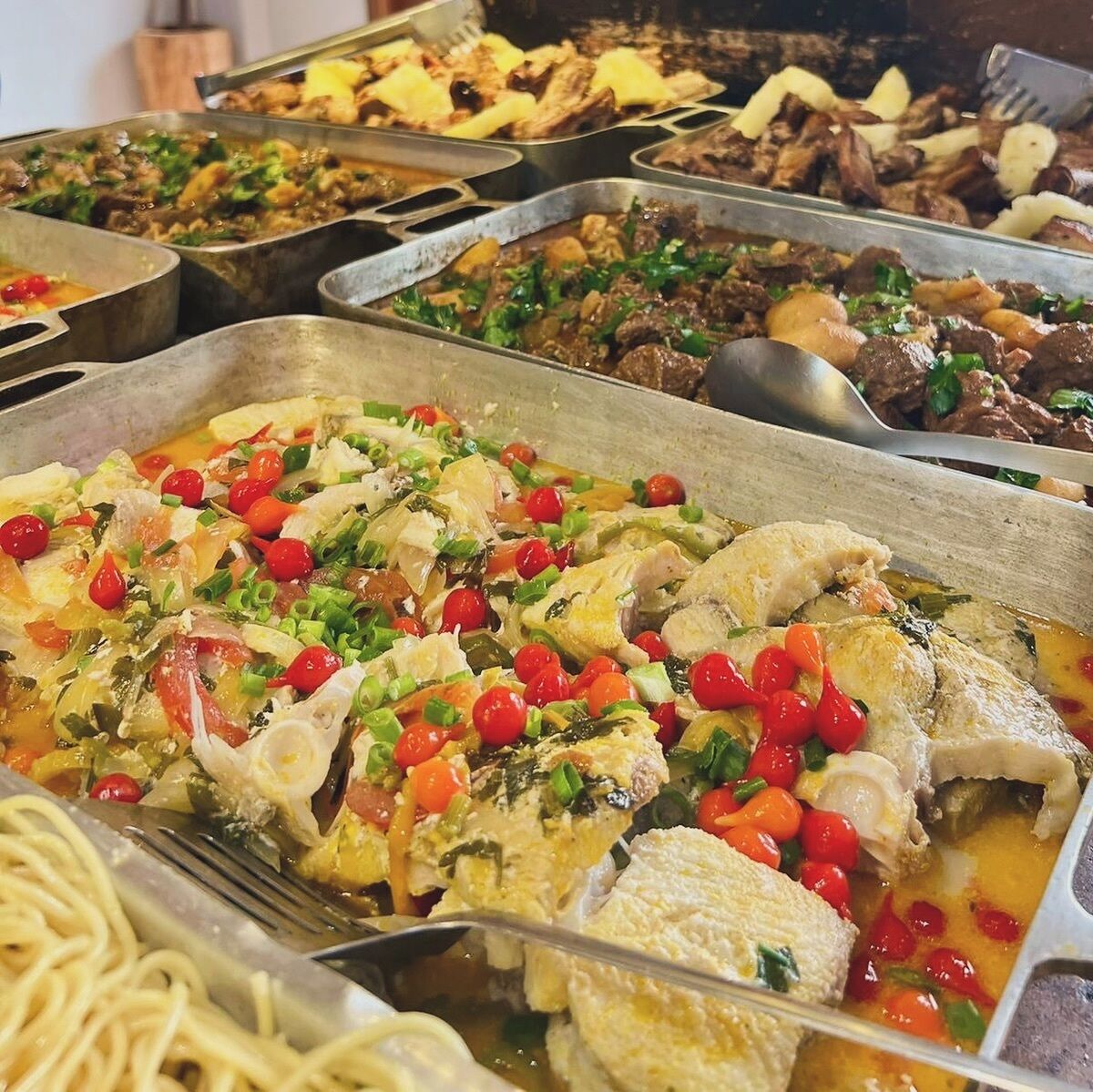 Un buffet con diversi piatti, tra cui pesce, verdure e carni.