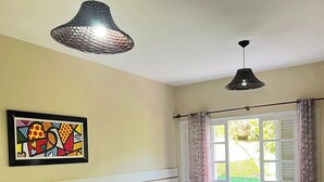 Een hotelkamer met twee bedden, een groot raam met gordijnen, een kleurrijk kunstwerk aan de muur en twee hanglampen.