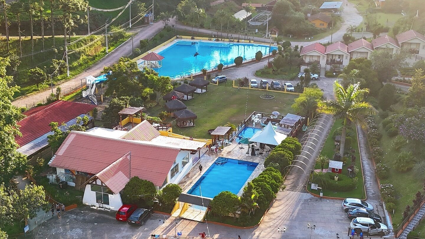 Ein Resort mit mehreren Schwimmbecken, einem überdachten Bereich und einem Parkplatz.