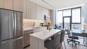 A modern kitchen with stainless steel appliances, a large window, and a dining area with a view. - Landing | Modern 1BD, Yoga Studio, Gym (Chicago)