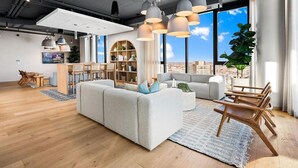 A modern living room with a sectional sofa, dining area, and large windows with a city view. - Landing | Beautiful 1BD, Yoga Studio, Pool (Chicago)