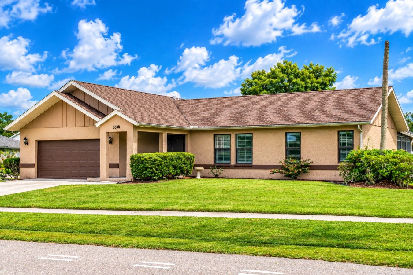 A single-story house with a brown garage, a chimney, and a well-maintained lawn.